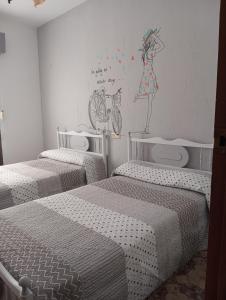 a room with three beds and a painting on the wall at El descanso soberano in Ossa de Montiel