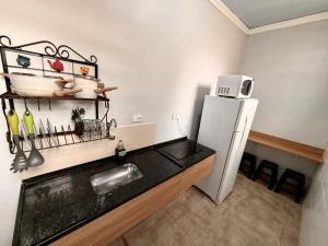 a kitchen with a refrigerator and a counter with a microwave at Marmeu Pitangueiras in Guarujá