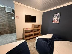 a bedroom with two beds and a tv on the wall at Marmeu Pitangueiras in Guarujá