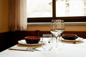 a table with two wine glasses and bowls on it at Hotel Chalet Seggiovia in Pontechianale