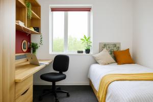 a bedroom with a bed and a desk with a laptop at Dunham Halls Manchester Met in Manchester