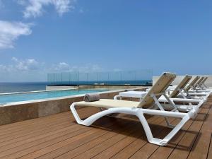 abba Suites Playa del Carmen في بلايا ديل كارمن: صف من كراسي الجلوس على سطح بجانب مسبح
