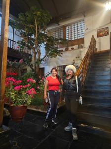 dos mujeres de pie en las escaleras de un edificio en Hostal el Conquistador, en Cusco