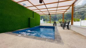 ein Swimmingpool in einer grünen Wand mit einem Tisch und Stühlen in der Unterkunft La Villa de Luci in Juivi