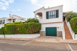 a white house with a green garage at Villa Cala Llonga in Cala Llonga