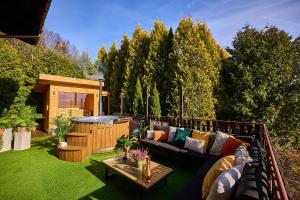 a patio with a couch and a hot tub at Villa Beskidzka 100 - SAUNA & BALIA z Jacuzzi Widok na góry i jezioro żywieckie in Zarzecze