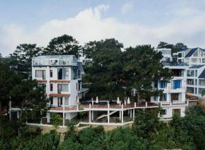 阿普春安Hotel Des Pins Dalat的一座前面有树的大型白色建筑