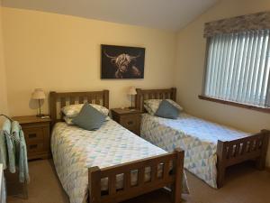 ein Schlafzimmer mit zwei Betten und einem Fenster in der Unterkunft Hopeman Cottages in Hopeman