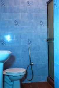 a blue tiled bathroom with a toilet and a hose at New Auto Motel in Barcelona
