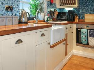 a kitchen with white cabinets and a sink at Cwrt in Dwyran