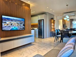 a living room and kitchen with a flat screen tv on a wall at CURTA!|216|Brava Arts|2 Suítes| Sofisticada Vista in Cabeçudas