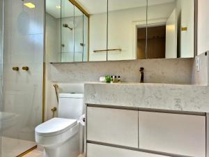 a bathroom with a toilet and a sink and a mirror at CURTA!|216|Brava Arts|2 Suítes| Sofisticada Vista in Cabeçudas +19 photos