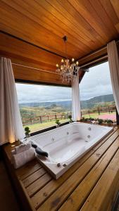 a large tub in a room with a large window at Vale Encantado Alfredo Wagner in Barracão
