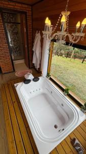 a large white tub in a room with a window at Vale Encantado Alfredo Wagner in Barracão