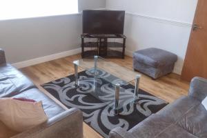 a living room with a couch and a table and a tv at Doncaster Dream House Retreat- Sleeps 9 in Doncaster