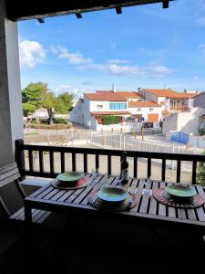 d'une table en bois avec des assiettes au-dessus d'un balcon. dans l'établissement Spacieux appartement tout confort proche plage et centre ville Wifi Animaux bienvenus, à Saintes-Maries-de-la-Mer