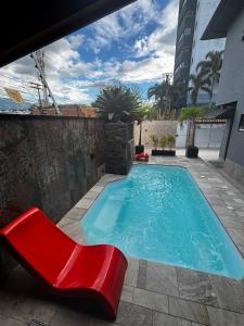 einen Pool mit einer roten Bank und einem roten Stuhl in der Unterkunft Casa Pé na Areia com Piscina Climatizada in Bertioga