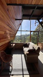 ein Wohnzimmer mit Couch und großem Fenster in der Unterkunft Chale Pedra do Sol in Caxias do Sul