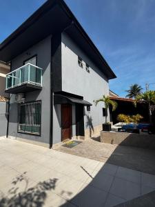 ein weißes Haus mit einem Balkon darauf in der Unterkunft Casa Pé na Areia com Piscina Climatizada in Bertioga