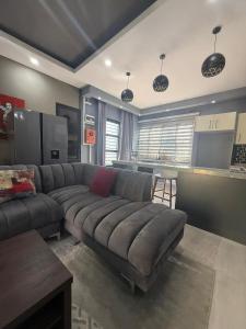 a living room with a large couch and a kitchen at Infinity Apartments in Lusaka