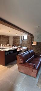 a living room with a leather couch and a kitchen at Manoir de Kerenneur in Plourin