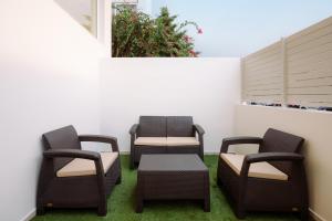 3 sedie e un tavolo su un patio con prato di South Metro Loft ad Atene