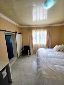 a bedroom with a bed and a window with a chair at Sweet Home B & B in East London +10 photos