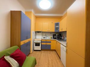 a kitchen with yellow and blue cabinets and a green couch at Comfy - Old town apartment Bratislava in Staré Mesto