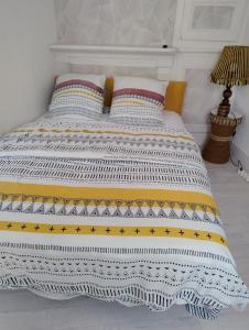 Una cama con una manta blanca y amarilla. en Gite Iza, en Lormes
