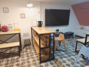 Una sala de estar con televisión, una mesa y un escritorio. en 레토하우스, en Incheon