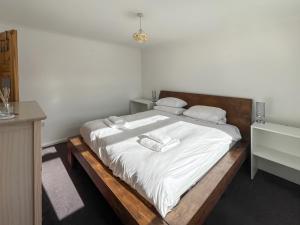 a bedroom with a bed with white sheets and towels at Springfield Bungalow in Cliftonville