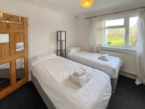 two beds in a room with a window at Springfield Bungalow in Cliftonville