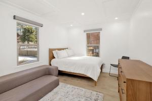 ein weißes Schlafzimmer mit einem Bett und einer Couch in der Unterkunft Vista Pines at Big Bear Lake– Your Ultimate Mountain Escape in Big Bear Lake