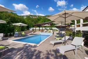 ein Pool mit Stühlen und Sonnenschirmen neben einem Gebäude in der Unterkunft Luxury villa with a swimming pool Dolinci, Crikvenica - 13914 in Grižane