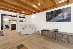 ein Wohnzimmer mit einem weißen Stuhl und einem TV in der Unterkunft Vista Pines at Big Bear Lake– Your Ultimate Mountain Escape in Big Bear Lake