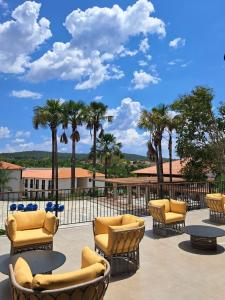 a group of chairs and tables on a patio with palm trees at Resort Quinta Santa Barbara in Pirenópolis