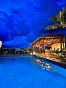a pool at night with a gazebo and a palm tree at Resort Quinta Santa Barbara in Pirenópolis