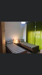 trois lits dans une chambre avec un rideau vert dans l'établissement Casa Vacanze Piazza Europa, à Milazzo 4 autres photos
