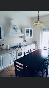 une cuisine avec une table et des chaises et une cuisine avec des armoires blanches dans l'établissement Casa Vacanze Piazza Europa, à Milazzo