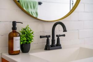 a bathroom sink with a bottle of soap and a mirror at Jungle House Columbus Sleep 16 Downtown Ohio Free Parking - Near Convention Center & Nationwide Arena - 4BR Luxury Home - Pet Friendly - Over 5,800 Five Stars in Columbus +96 photos