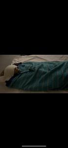 a person laying on a bed with a blanket at AISHAMA Healing House in Aït Ourir