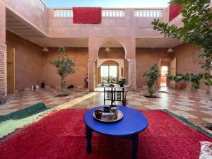 a large room with a blue table and a red rug at AISHAMA Healing House in Aït Ourir