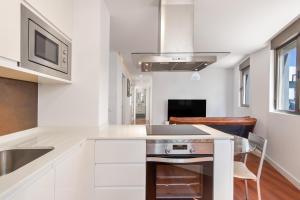 a kitchen with white cabinets and a sink and a microwave at Ínsula Home in Tamaraceite