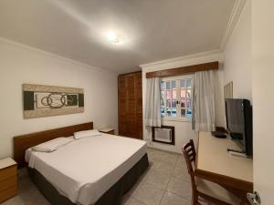 ein Hotelzimmer mit einem Bett und einem Fernseher in der Unterkunft Flat estudio 110 Amarilis Riviera de São Lourenço, 03 piscina climatizada, serviço de hotelaria, limpesa e troca de toalhas diária, carregador veiculo elétrico e servico de praia finais de semana WiFi 500 in Riviera de São Lourenço + 100 Fotos