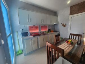 a kitchen with white cabinets and a wooden table with a dining room at Apartamento T1 Mobilado Espargos/Sal in Espargos