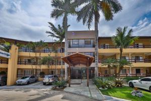 ein Gebäude mit Palmen davor in der Unterkunft Flat estudio 110 Amarilis Riviera de São Lourenço, 03 piscina climatizada, serviço de hotelaria, limpesa e troca de toalhas diária, carregador veiculo elétrico e servico de praia finais de semana WiFi 500 in Riviera de São Lourenço