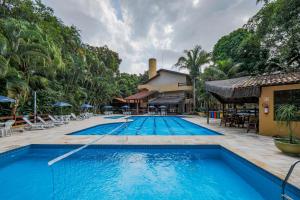 einen Pool in einem Resort mit Tischen und Stühlen in der Unterkunft Flat estudio 110 Amarilis Riviera de São Lourenço, 03 piscina climatizada, serviço de hotelaria, limpesa e troca de toalhas diária, carregador veiculo elétrico e servico de praia finais de semana WiFi 500 in Riviera de São Lourenço