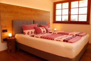 une chambre avec un grand lit avec des oreillers rouges et blancs dans l'établissement Ferienwohnung Holzfäller, à Vorderfalkau