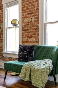 a green couch in a room with a brick wall at Jungle House Columbus Sleep 16 Downtown Ohio Free Parking - Near Convention Center & Nationwide Arena - 4BR Luxury Home - Pet Friendly - Over 5,800 Five Stars in Columbus