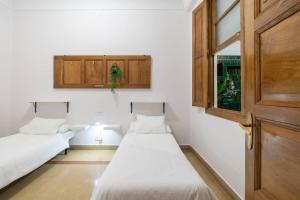 two beds in a room with white walls and wooden cabinets at Casa Bogart Apto 5 dormitorios in Ourense